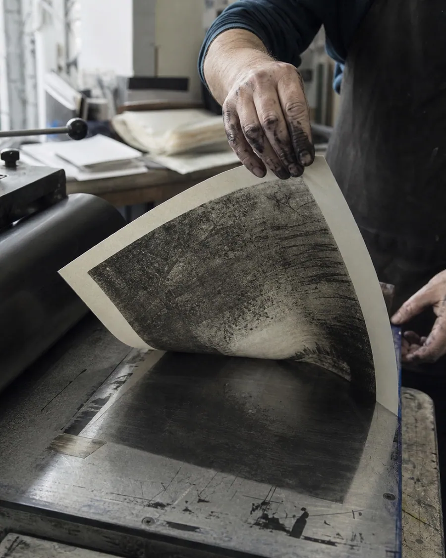 An artist pulling a fresh print by hand in the studio